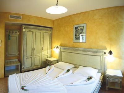 Camera d'hotel con letto matrimoniale, pareti gialle e mobili classici in legno.