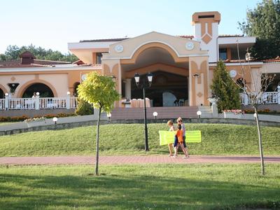 Großes Hotelgebäude mit Arkaden, davor ein Garten mit Bänken und einem Spaziergänger