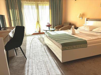 Camera d'hotel accogliente con letto matrimoniale, scrivania, sedia e balcone con tende.