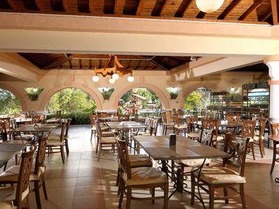 Area pranzo aperta con tavoli e sedie in legno sotto un soffitto con travi in legno