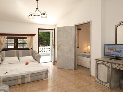 Camera d'hotel luminosa con divano, balcone e bagno adiacente con vasca da bagno.