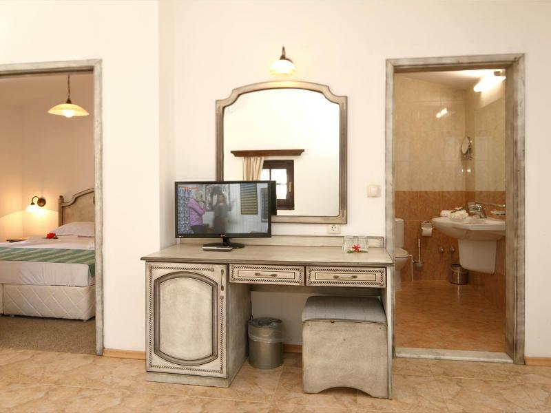 Una stanza con un tavolo da trucco, uno specchio e porte che conducono alla camera da letto e al bagno.