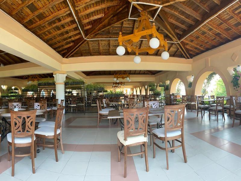 Ampia sala da pranzo aperta con sedie in legno e finestre ad arco sotto un soffitto in legno