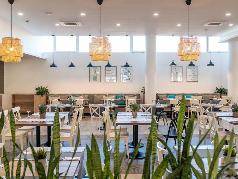 Bright, modern restaurant with plants, wooden tables, and stylish lighting.