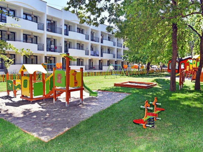 Colorful children's playground equipment in front of a multi-story hotel building