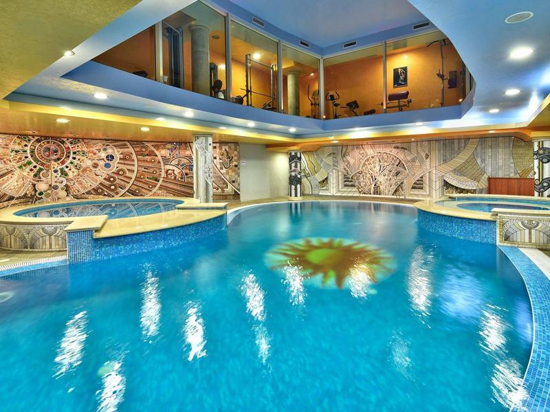 Indoor pool with blue water and artistic wall decorations inside a hotel.