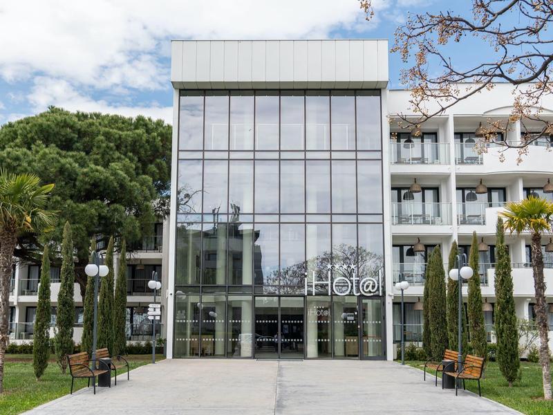 Modern hotel entrance with large glass windows and green front garden