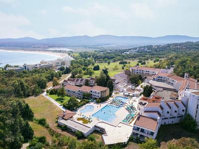 Complesso alberghiero con piscina vicino a una spiaggia e colline boschive sullo sfondo