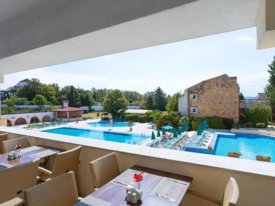 Außenbereich eines Hotels mit Pool und Terrasse, Tische mit Stühlen im Vordergrund.