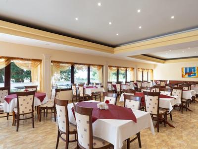 Sala da pranzo luminosa con tavoli e sedie, decorata con tovaglie e corsie rosse.