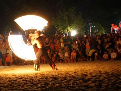 Feuershow am Strand vor einer großen Zuschauergruppe bei Nacht.