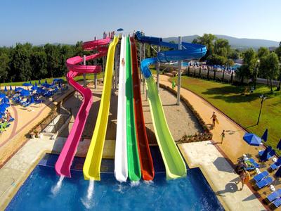 Scivoli d'acqua colorati che conducono a una piscina in un parco acquatico soleggiato con lettini.