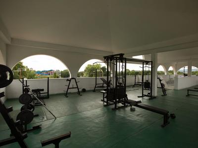 Fitnessraum mit Krafttrainingsgeräten und großen Fenstern mit Blick auf den Garten.