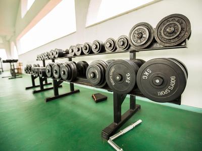 Lang gestreckter Raum mit einer Reihe von Hanteln auf einem schwarzen Ständer vor großen Fenstern.