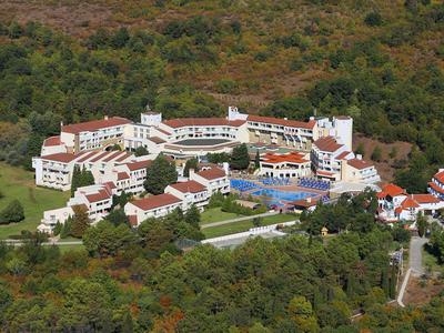 Große Hotelanlage mit Pool, umgeben von dichtem Wald und hügeliger Landschaft.