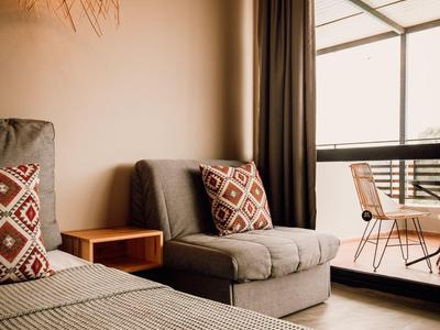 Gezellige hotelkamer met bed, bank, decoratieve kussens en balkon met uitzicht.