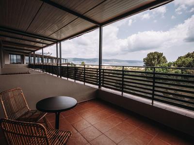 Balkon met stoelen en tafel met uitzicht op bomen en lucht.