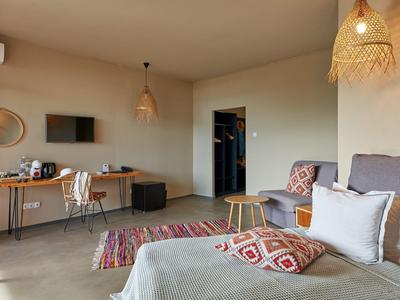 Modern ingerichte hotelkamer met zithoek, bureau en warme kleuren in het decor.