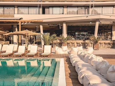 Moderne hotelzwembad met ligstoelen en comfortabele zitzakken naast het water