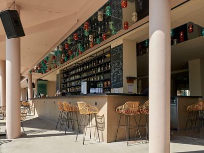 Area bar esterna moderna con sgabelli alti e scaffali pieni di bottiglie.