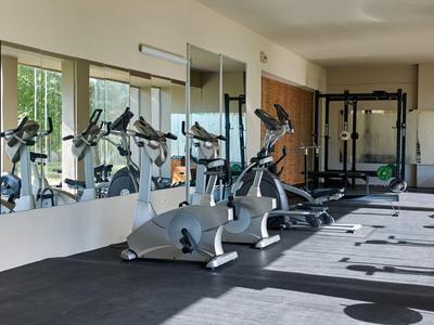 Palestra moderna con attrezzature cardio e grandi specchi in una stanza luminosa.