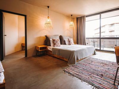 Modern hotelkamer met tweepersoonsbed, kleed, balkon en warm licht.