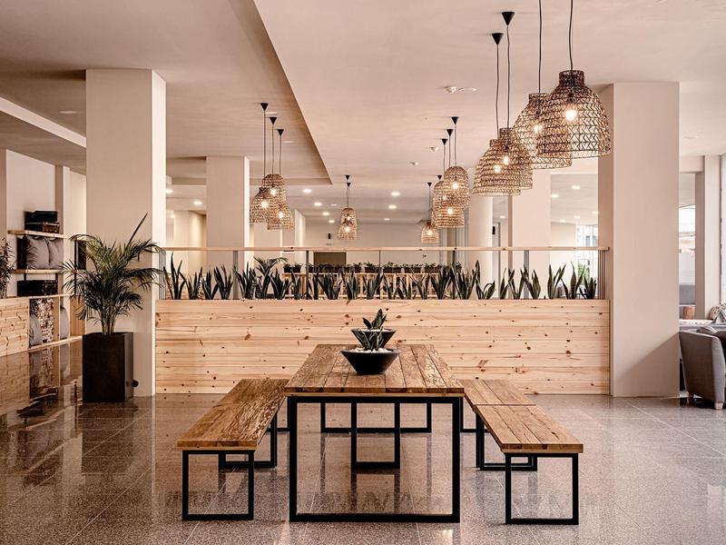 Lichte moderne eetruimte met houten tafels en hanglampen in een hotel.