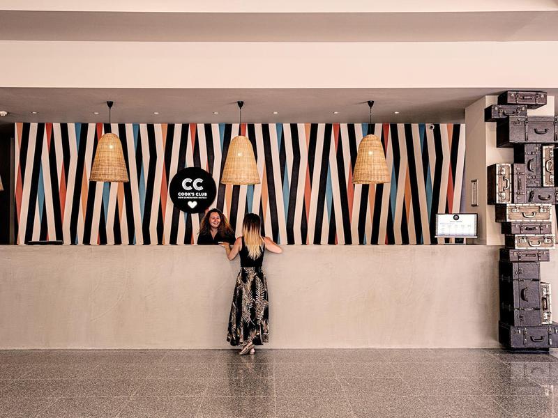 Groot buitenzwembad met ligstoelen en parasols voor een hotelgebouw.