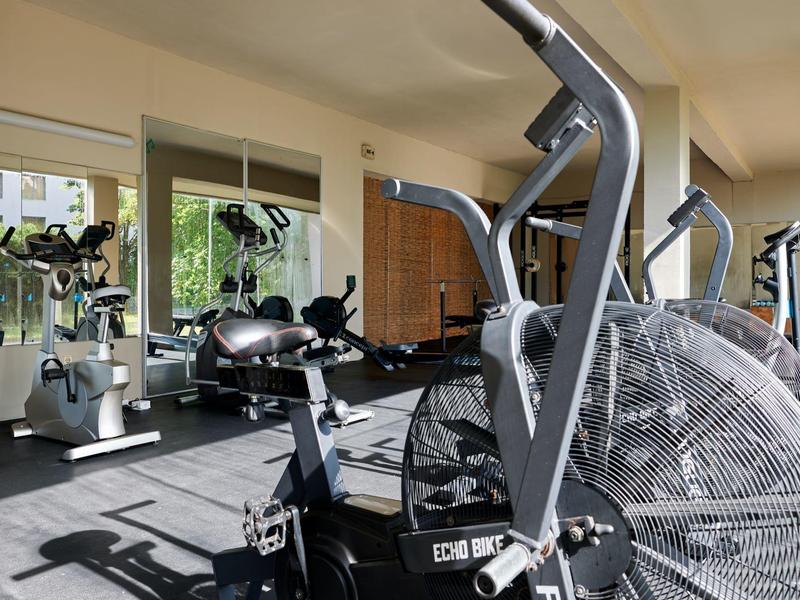 Moderne fitnessapparatuur in een lichte, goed uitgeruste sportschool van een hotel met spiegelwand.