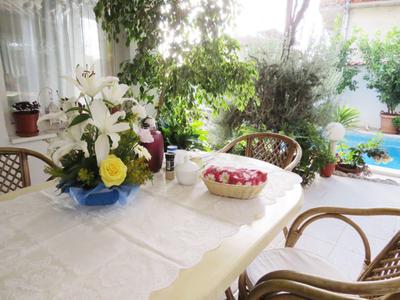 Tisch mit weißer Tischdecke, Blumenstrauß, Korb mit Erdbeeren und Stühlen im grünen Garten.