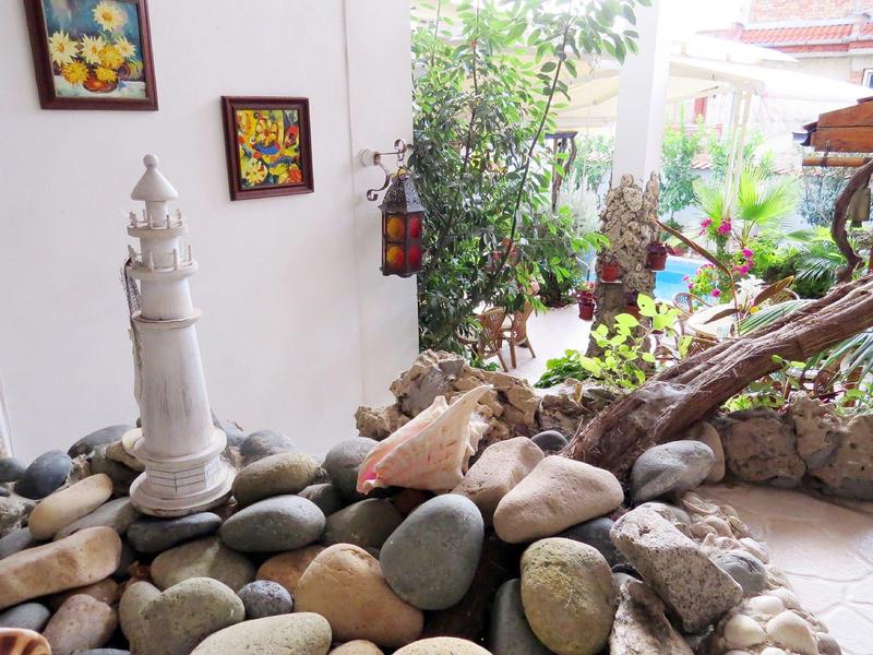 Ein heller Wintergarten mit glatten Steinen, weißem Leuchtturm-Dekor und Pflanzen im Hintergrund.