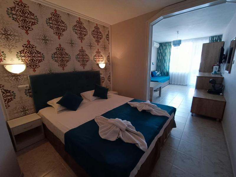 Gemütliches Hotelzimmer mit Doppelbett, blauen Akzenten und offenem Durchgang zu einem zweiten Raum.