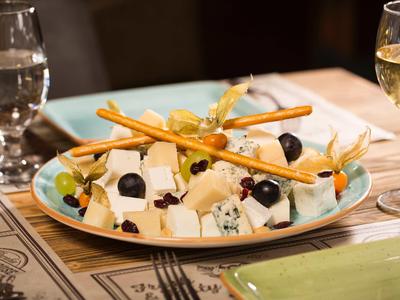 Vorspeisenteller mit Käsewürfeln, schwarzen Oliven und Brotstangen auf einem Tisch.