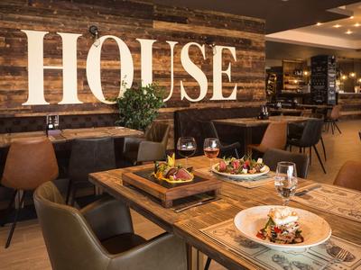 Gemütliches Restaurant mit Holztischen, Lederstühlen und eleganter Speisenpräsentation.