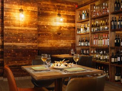 Gemütlicher Essbereich mit Holzwänden, Weinregalen und gedecktem Tisch für vier Personen.