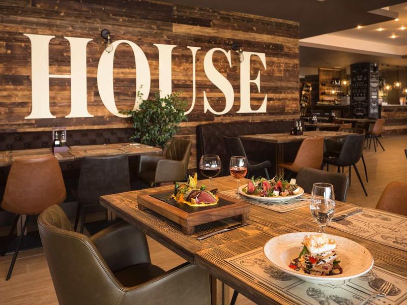 Gemütliches Restaurant mit Holzwänden, braunen Ledersesseln und gedeckten Tischen mit Speisen.