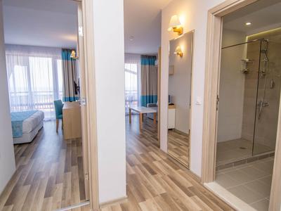 Heller Flur mit Holzfußboden, Zugang zu Badezimmer, Schlafzimmer und Wohnzimmer mit Vorhängen.