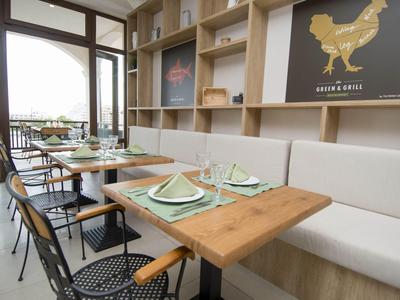 Modernes Restaurant mit Holztischen, bequemen Sitzbänken und großem Fenster mit Stadtblick.