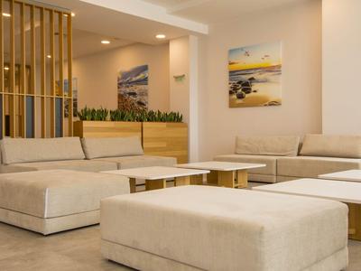 Moderner, heller Hotel-Loungebereich mit bequemen, cremefarbenen Sofas und minimalistischer Dekoration.