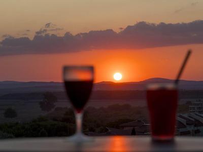 Sonnenuntergang über Hügeln mit verschwommenen Getränken im Vordergrund.