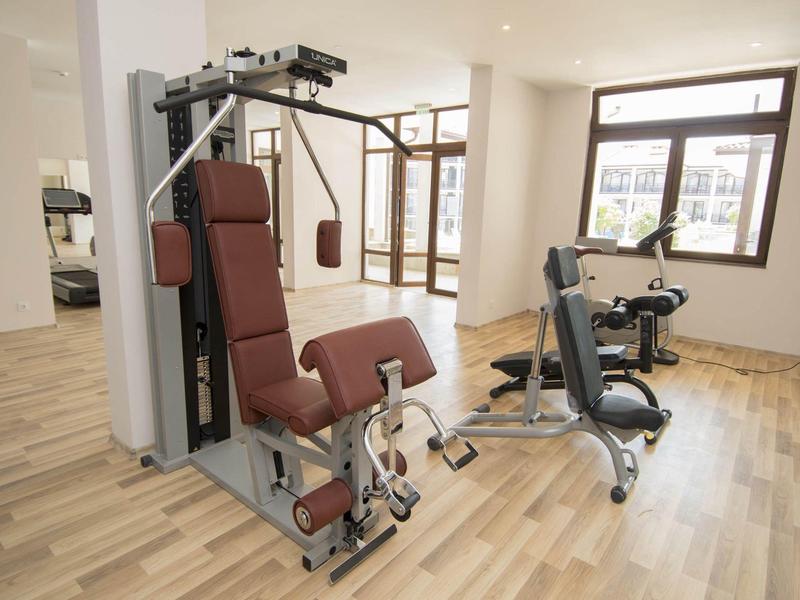 Kleiner, heller Fitnessraum mit Holzfußboden und zwei modernen Trainingsgeräten.