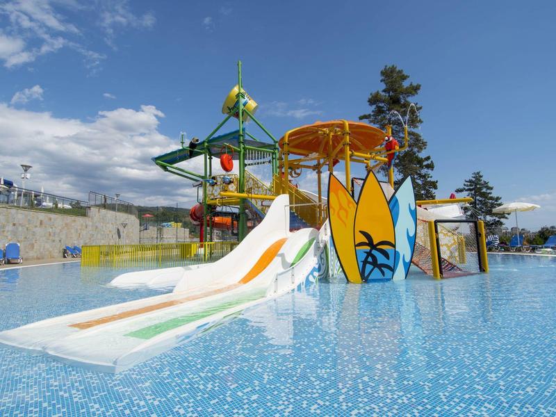 Wasserpark mit bunten Wasserrutschen und Planschbecken unter blauem Himmel.