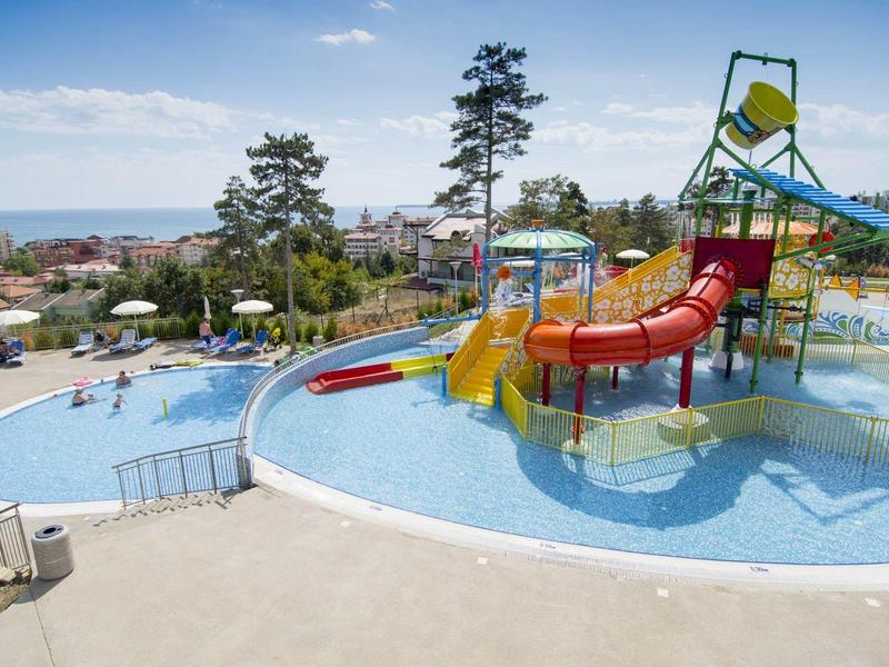 Wasserspielplatz mit bunten Rutschen und flachem Becken unter blauem Himmel.