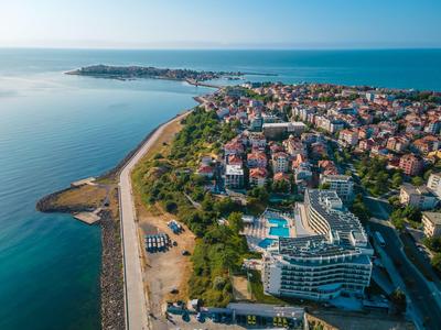 Vista aerea di una città costiera con hotel, spiaggia e piscina vicino al mare.