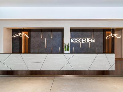 Moderna hall d'ingresso luminosa con bancone bianco e pareti scure.