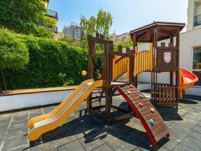 Area giochi all'aperto con scivolo e parete da arrampicata in un hotel o alloggio.