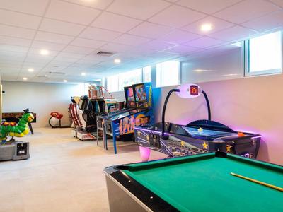 Pokój rekreacyjny z bilardem, air hockey i innymi grami w jasno oświetlonym pomieszczeniu.