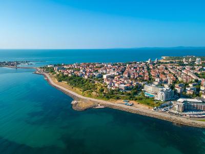 Veduta aerea di una città costiera con spiagge, edifici e mare azzurro limpido.