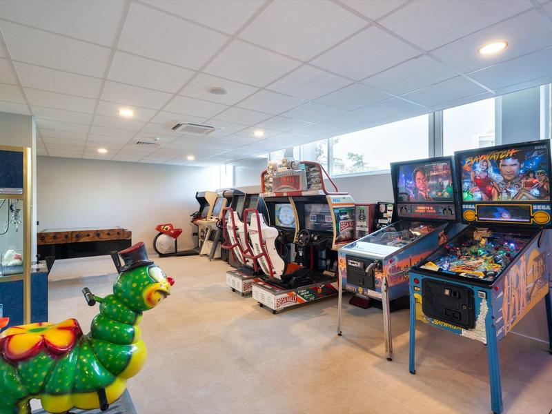 Sala ricreativa con videogiochi, flipper e un cavallo di carosello colorato in primo piano.