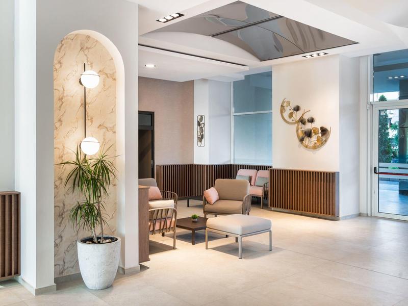 Area lounge moderna dell'hotel con divani comodi, tavoli e lampade da parete decorative.